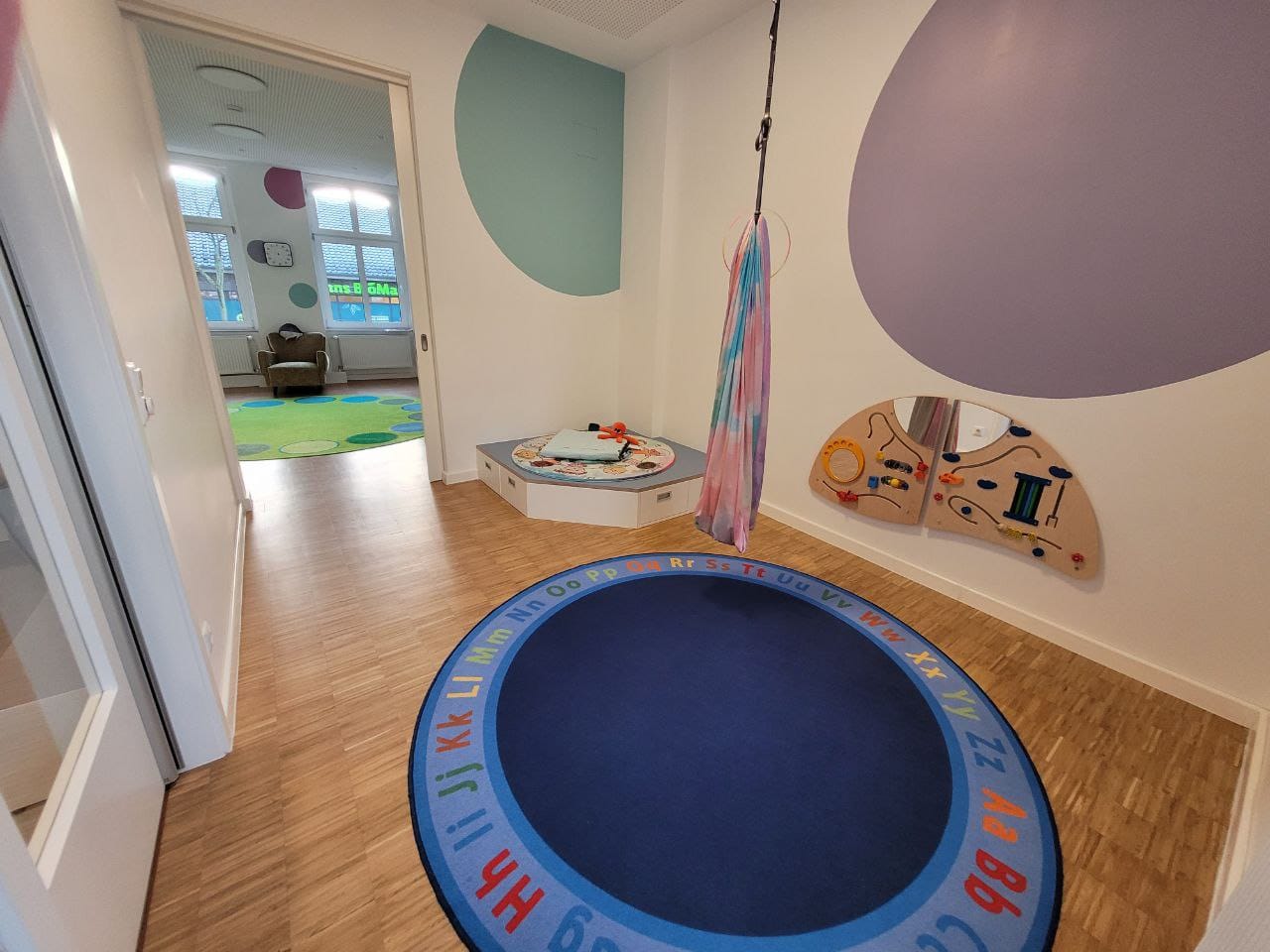 Bunte Spielzimmer mit einem Trampolin und einer Wandspieloberfläche.