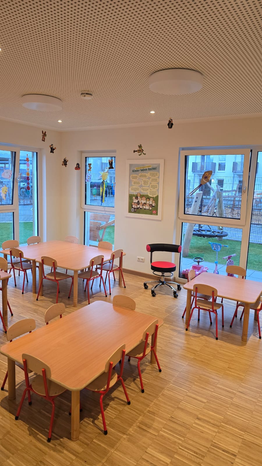 Helle, einladende Lernumgebung mit Tischen, Stühlen und Fenstern.