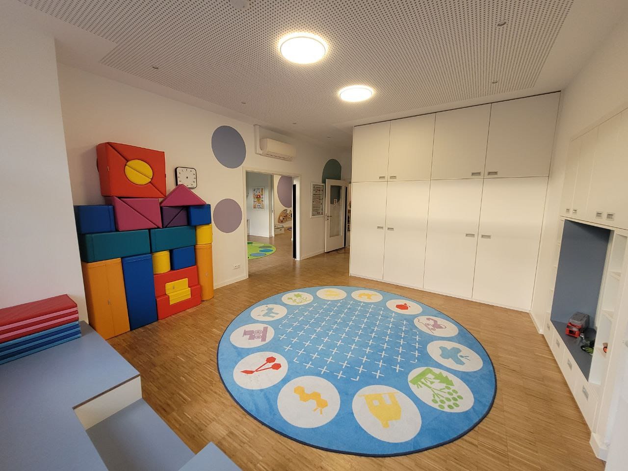 Bunte Spielzeugkiste und runder Teppich in einem hellen, freundlichen Spielzimmer.