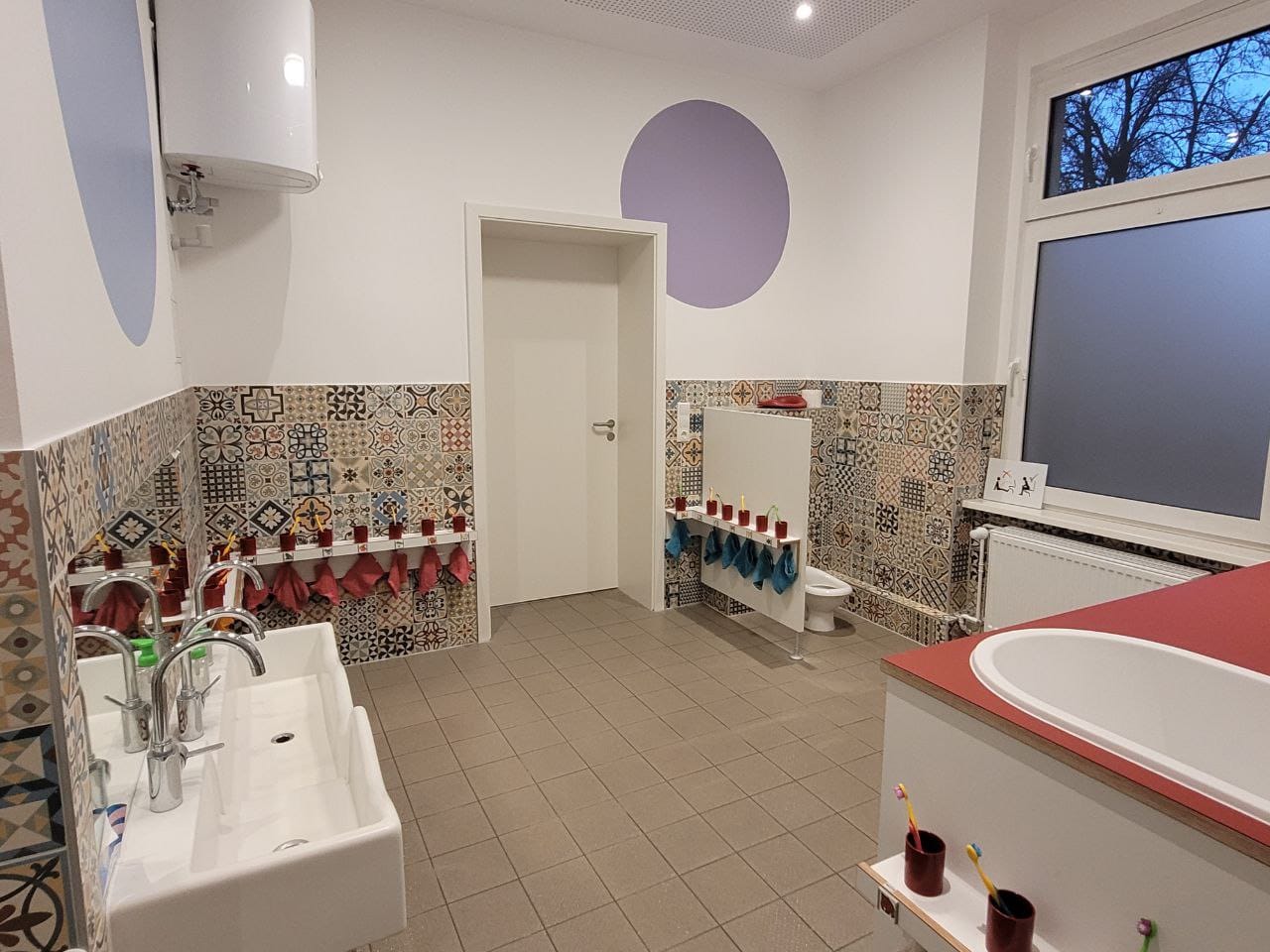 Badezimmer mit Waschbecken, Badewanne und bunten Fliesen an den Wänden.