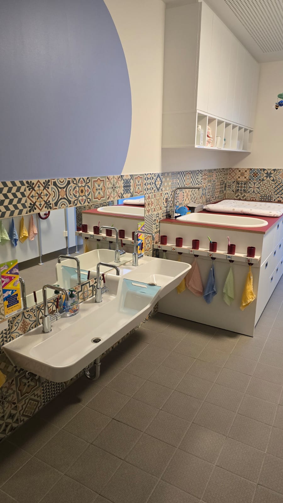 Waschbereich mit mehreren Waschbecken und farbigen Handtüchern in einem hellen Raum.